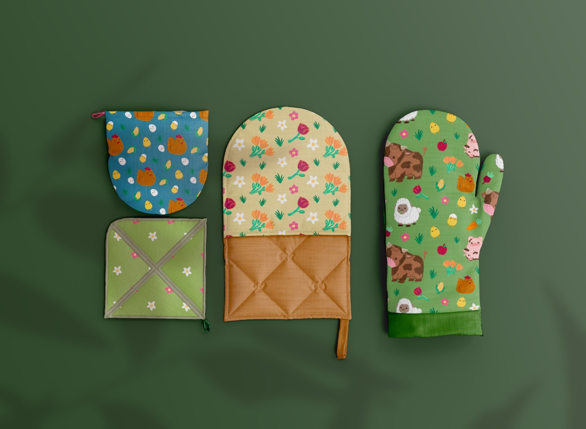 Oven mitts and pot holders in the Nikk Farm patterns on a green surface
